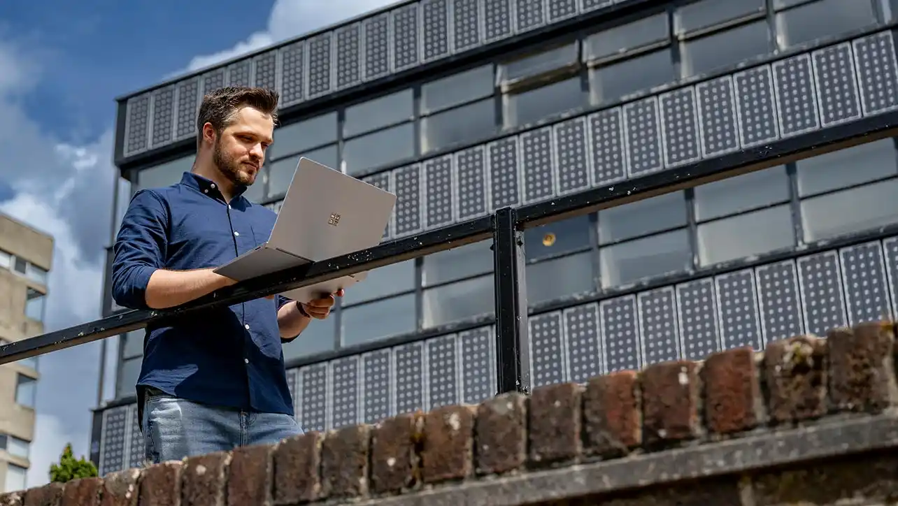 Management professional using a laptop outside an office building