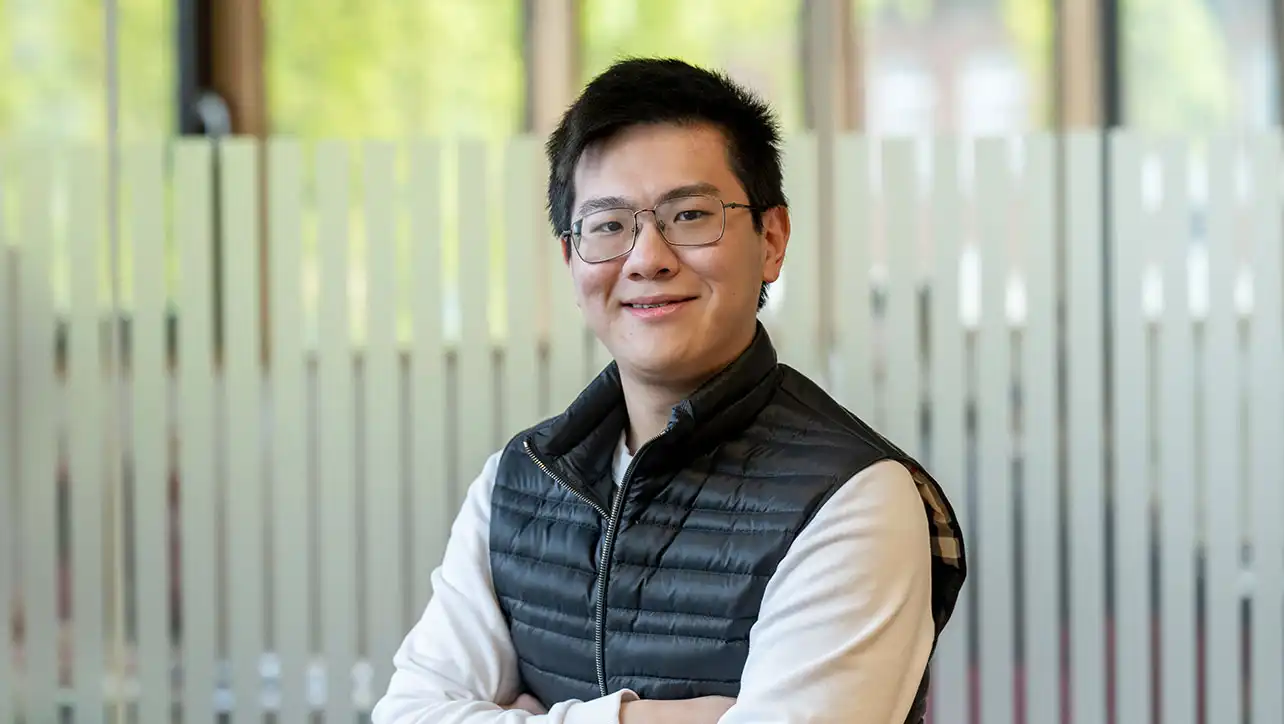 Student with arms folded smiling at camera