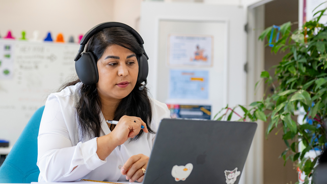 Female Southampton student wearing headphones and works on a laptop