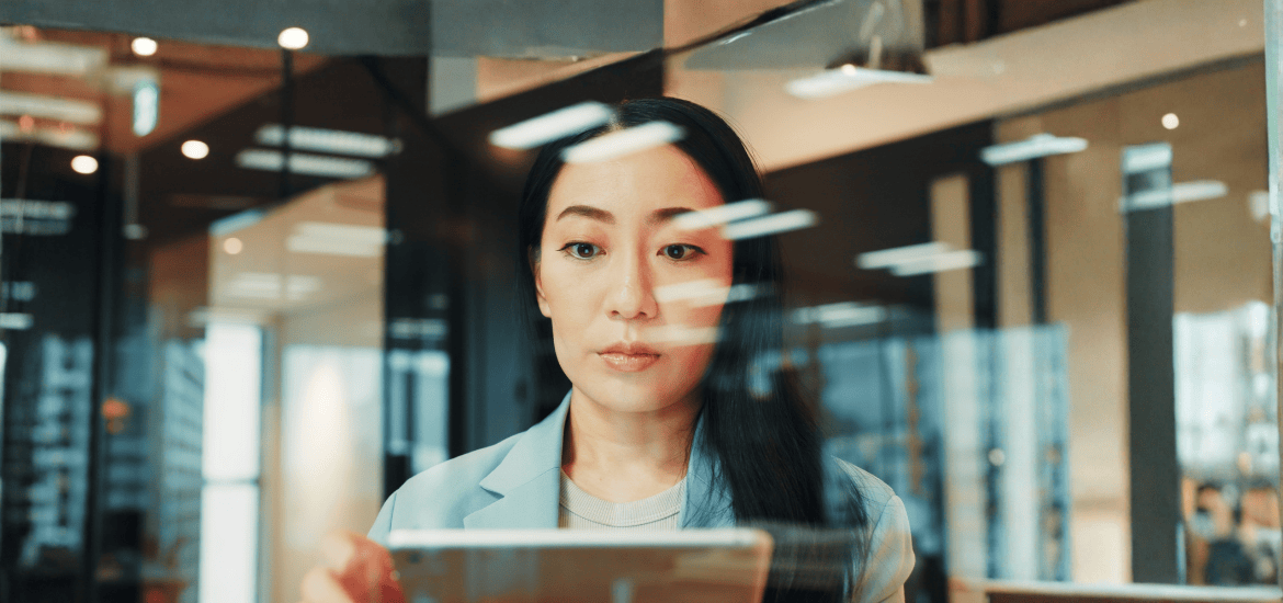 Woman looking at a laptop with reflective glass in front of her