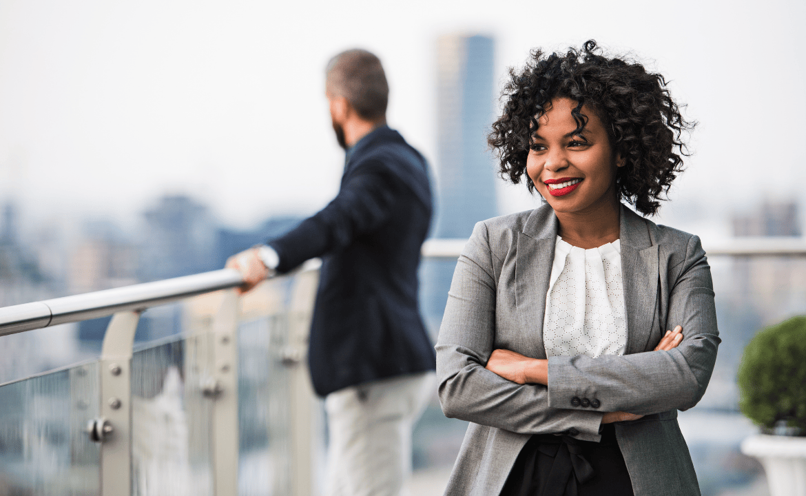 Woman stands on a city balcony in professional outfit