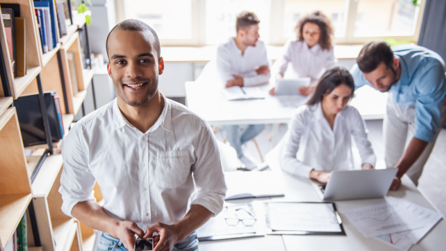 Male marketer holding a phone in an office