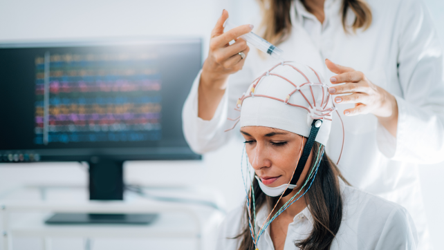 Researcher fitting an EEG cap on a participant, demonstrating brain research methods.