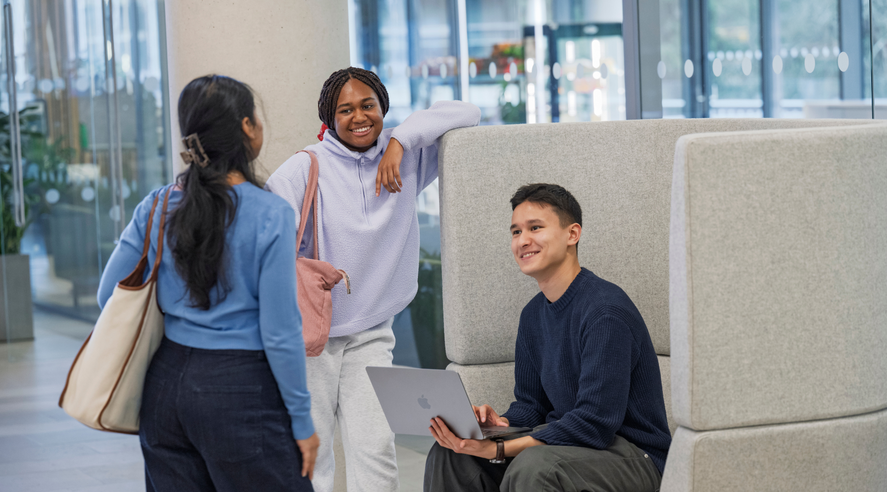 Three students talking together in a collaborative study space.