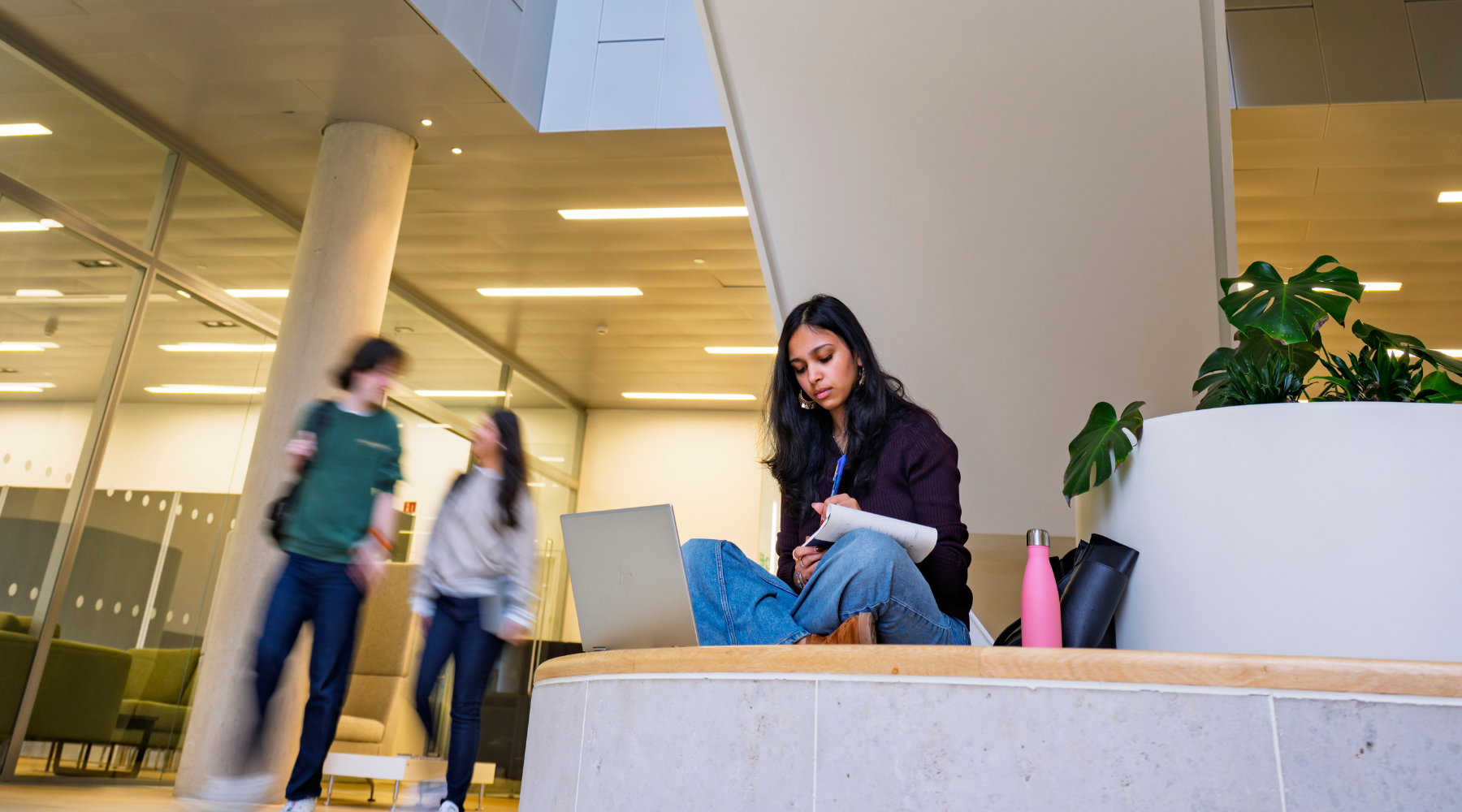 Student studying on a seating area in a university building.
